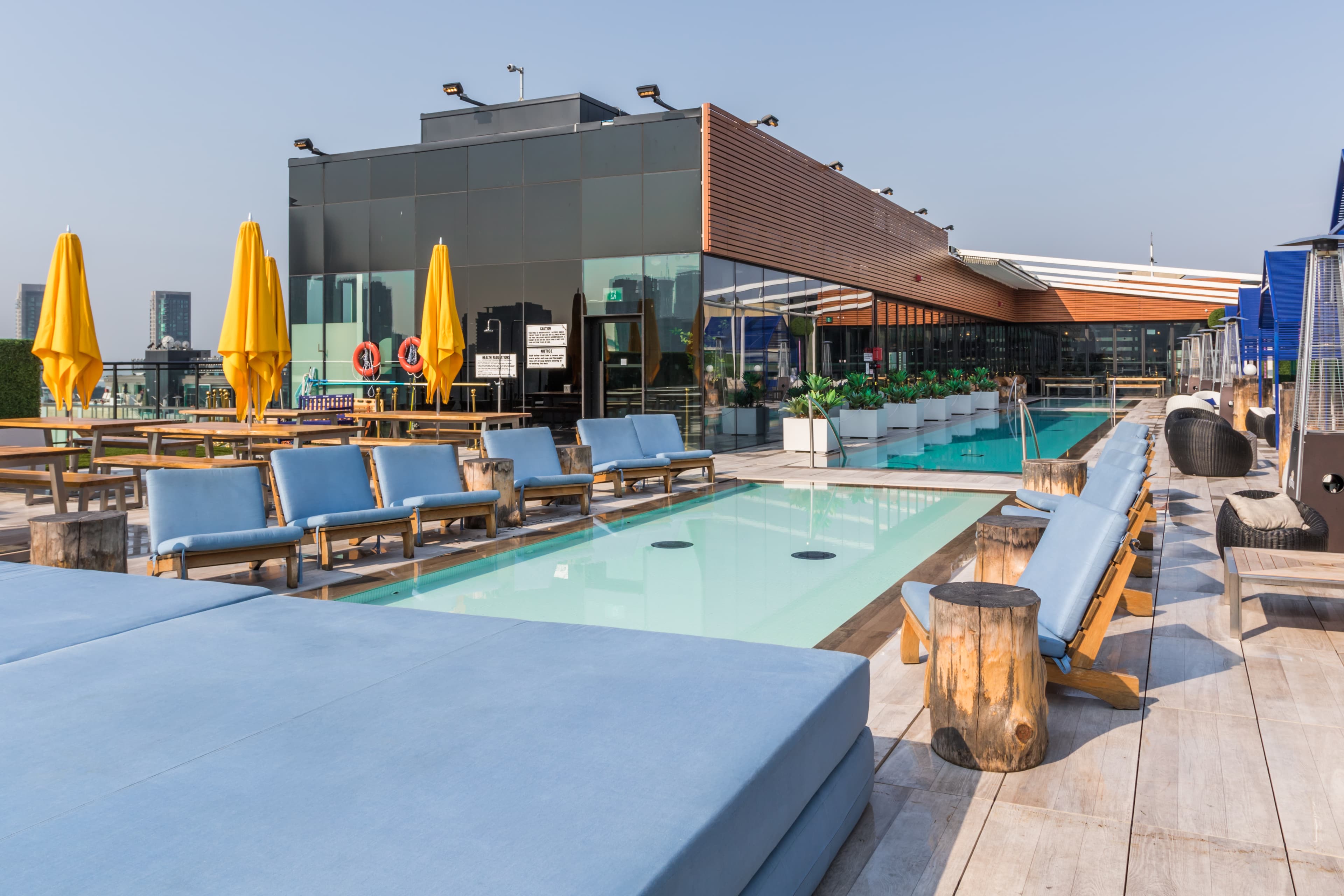 A landmark rooftop venue 16 stories above King West offering lounge bar, dining, outdoor pools, cabanas, and uninterrupted 360-degree skyline views. The layout organizes a progression from indoor dining, through a lounge bar, to terraces and pools, with private cabanas creating intimate moments at the edges of the rooftop. Luxurious finishes including sleek glazing, polished stone, warm wood tones, and soft ambient lighting complement reflective pool surfaces, while open sky and horizon views become central elements of the guest experience.