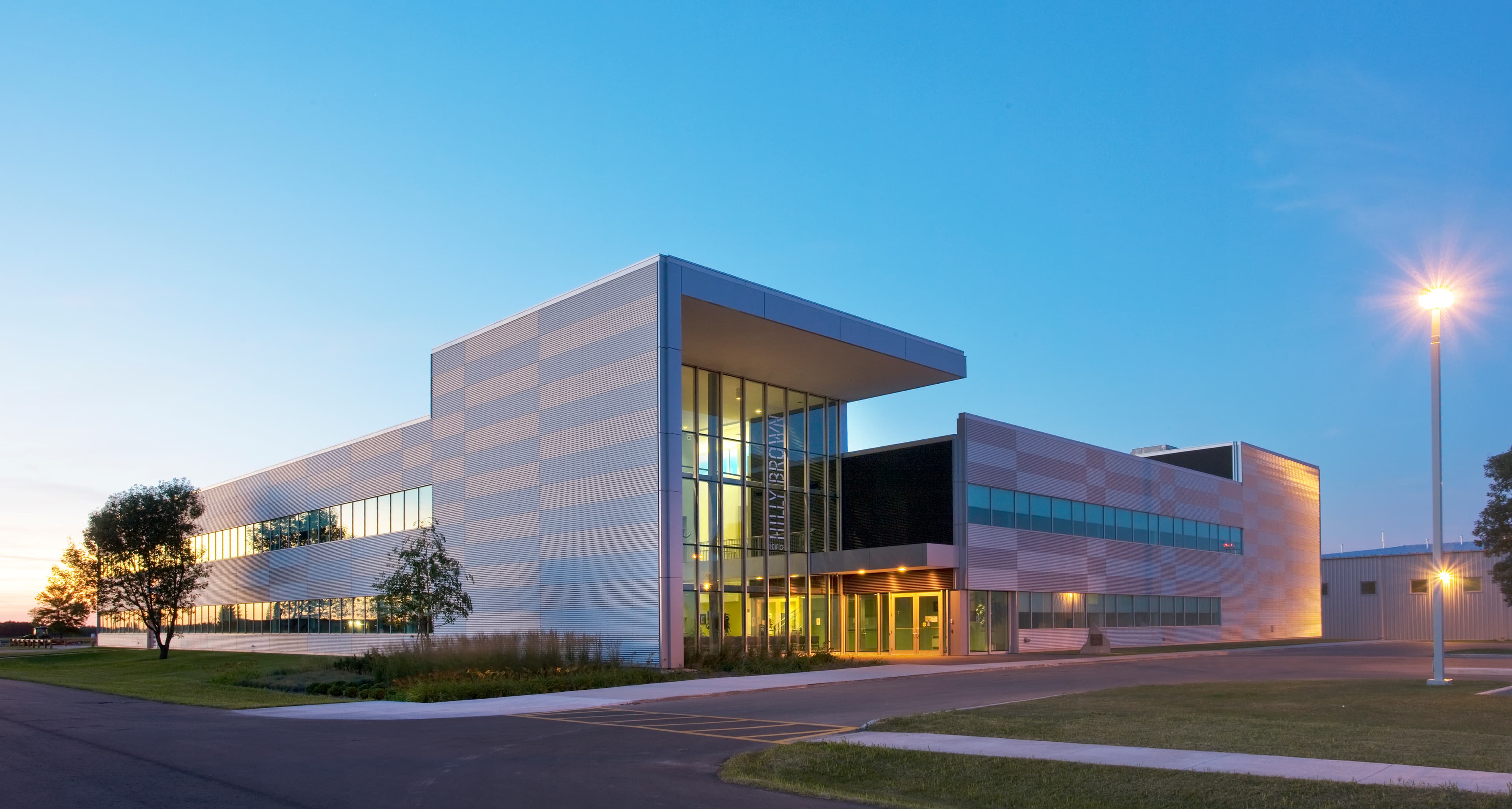 This 8,600 m² facility was designed as a central hub for flight training, integrating $65 million in advanced equipment including full-motion and fixed simulators. A clear plan organizes classrooms around a two-storey core, linked by bridges within a double-height corridor illuminated by clerestory windows. The exterior is clad in steel siding detailed in a silver-and-white checkerboard that echoes airfield markings, while polished concrete floors and bold accents animate the interior.