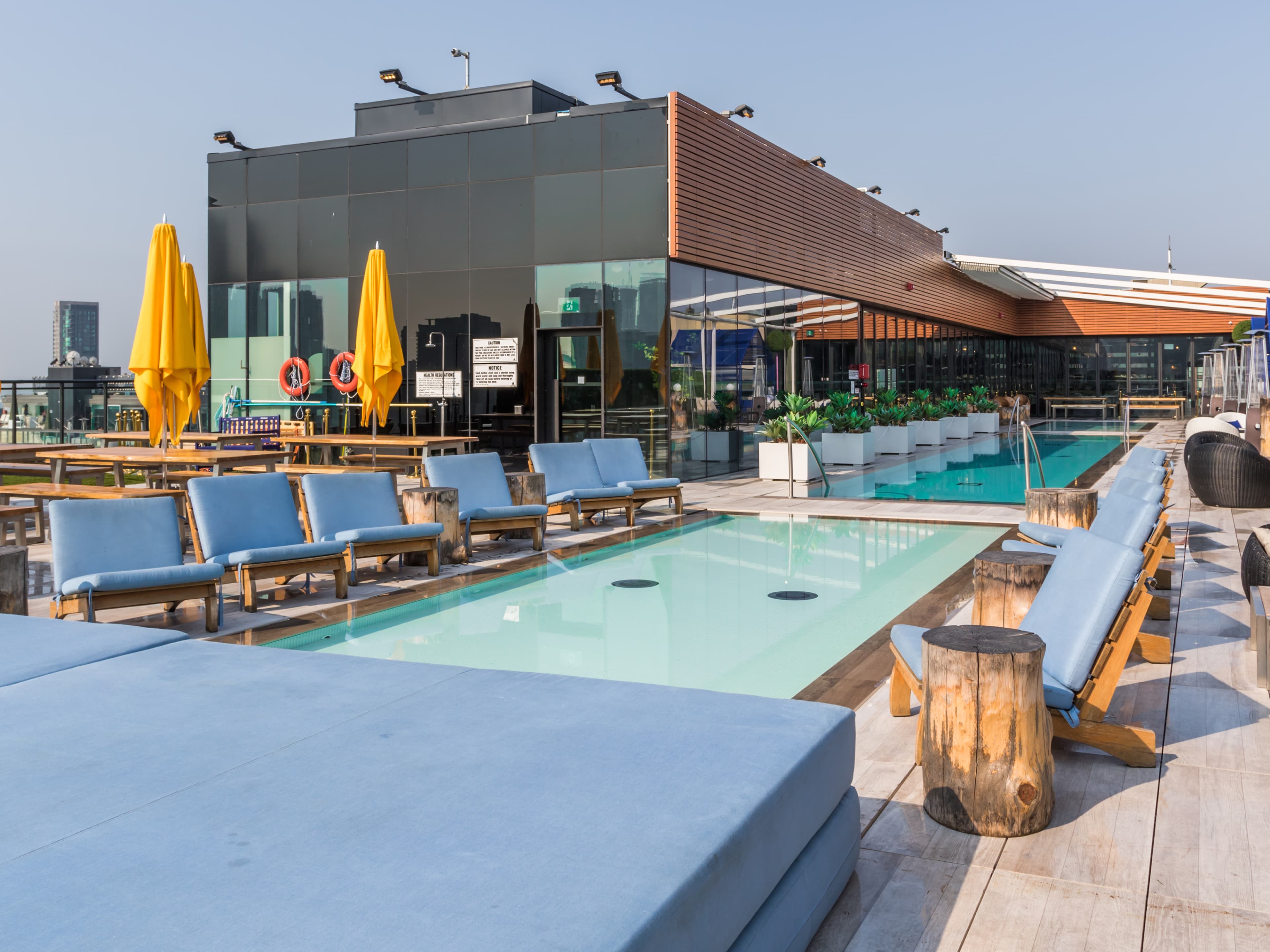 A landmark rooftop venue 16 stories above King West offering lounge bar, dining, outdoor pools, cabanas, and uninterrupted 360-degree skyline views. The layout organizes a progression from indoor dining, through a lounge bar, to terraces and pools, with private cabanas creating intimate moments at the edges of the rooftop. Luxurious finishes including sleek glazing, polished stone, warm wood tones, and soft ambient lighting complement reflective pool surfaces, while open sky and horizon views become central elements of the guest experience.