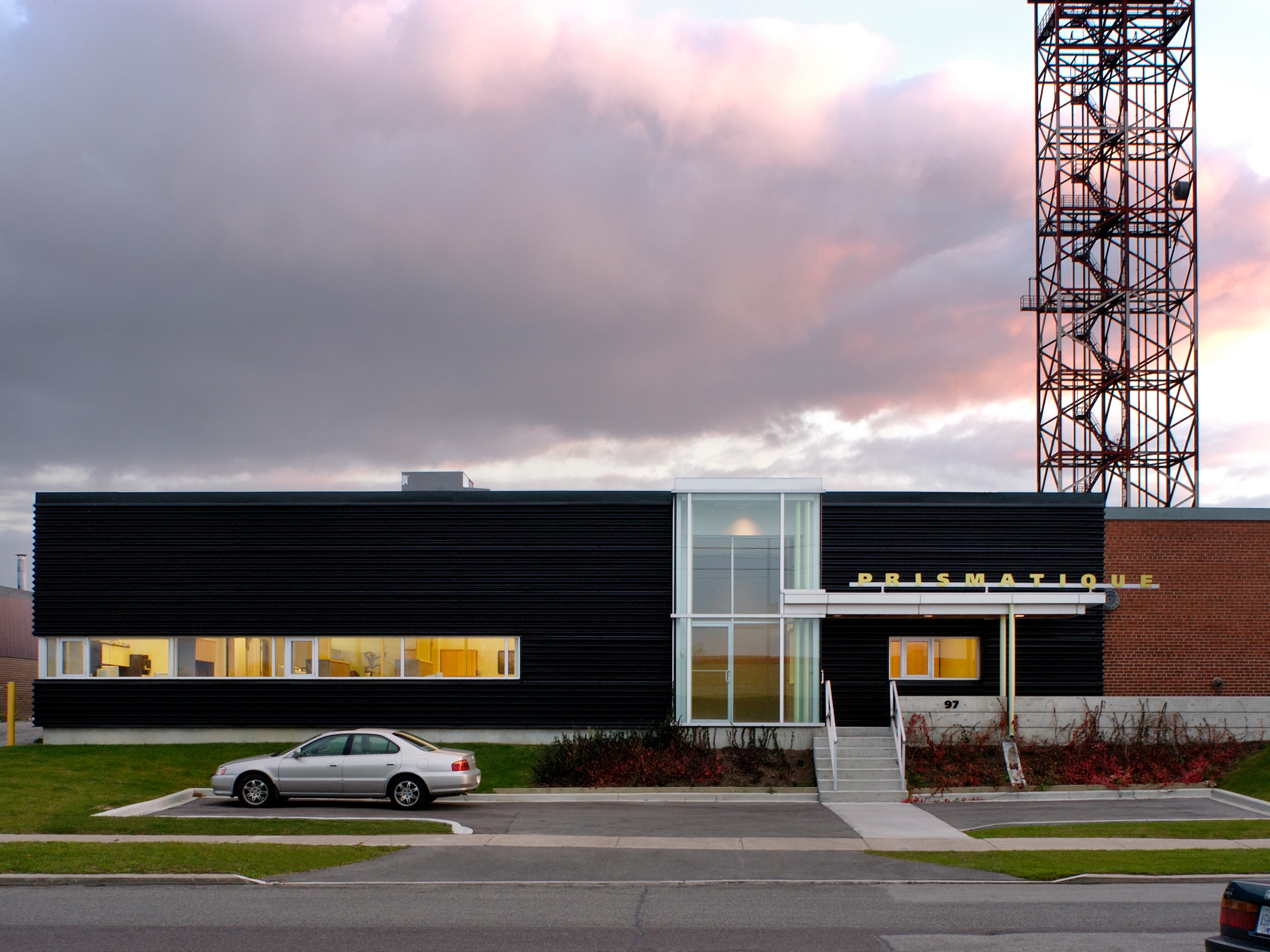 Renovations and additions refreshed the offices and main entry of this furniture manufacturer’s factory, strengthening its street presence and functionality. A lantern-like vestibule anchors the new entry, complemented by a canopy and walkways that connect to existing parking. Updated offices and a reconfigured parking court improve circulation while creating a more cohesive workplace environment.