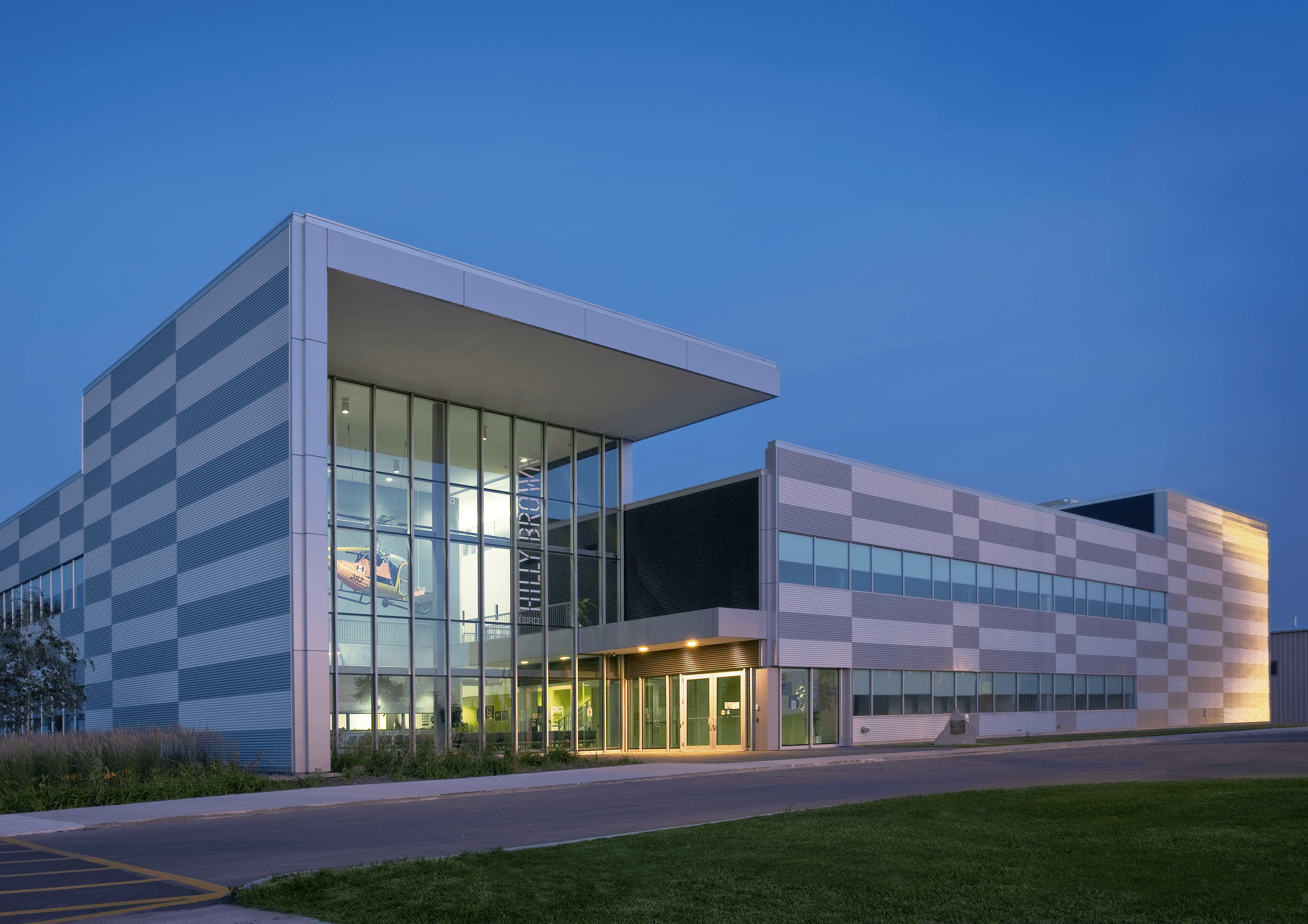 This 8,600 m² facility was designed as a central hub for flight training, integrating $65 million in advanced equipment including full-motion and fixed simulators. A clear plan organizes classrooms around a two-storey core, linked by bridges within a double-height corridor illuminated by clerestory windows. The exterior is clad in steel siding detailed in a silver-and-white checkerboard that echoes airfield markings, while polished concrete floors and bold accents animate the interior.